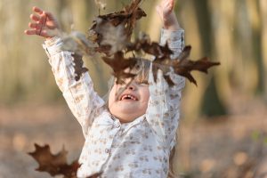 petite fille lançant des feuilles